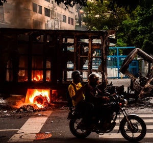 Dos personas pasan por delante de un camión calcinado en Venezuela Dos personas pasan por delante de un camión calcinado en Venezuela