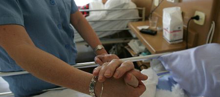 Un enfermo recibe la mano de una enfermera Un enfermo recibe la mano de una enfermera