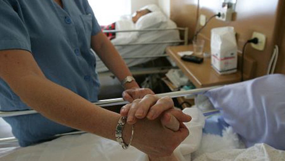Un enfermo recibe la mano de una enfermera