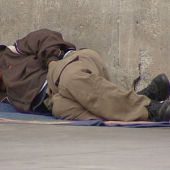 Un persona sin techo tumbado en la calle.