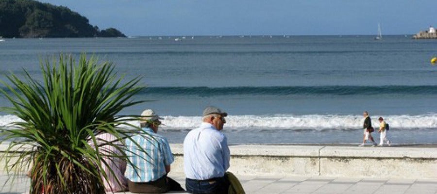 Unos jubilados sentados en un banco frente a la playa Unos jubilados sentados en un banco frente a la playa