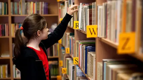 Niña en una biblioteca Niña en una biblioteca