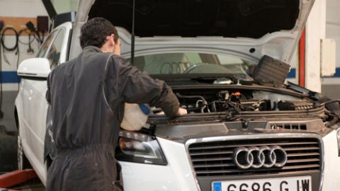 Un mec&aacute;nico arregla un autom&oacute;vil en un taller.