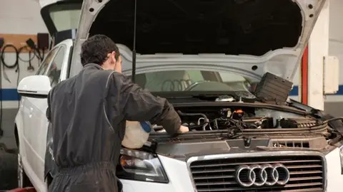Un mecánico arregla un automóvil en un taller. Un mecánico arregla un automóvil en un taller.