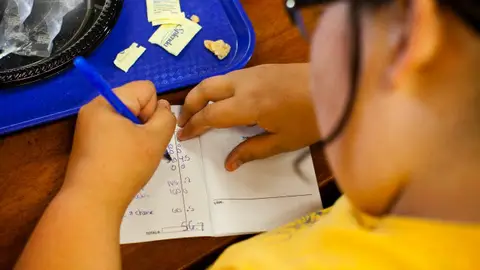 Niño haciendo los deberes después de comer Niño haciendo los deberes después de comer
