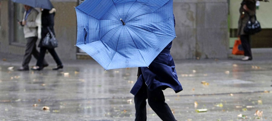 Una mujer se protege de la lluvia y el viento Una mujer se protege de la lluvia y el viento