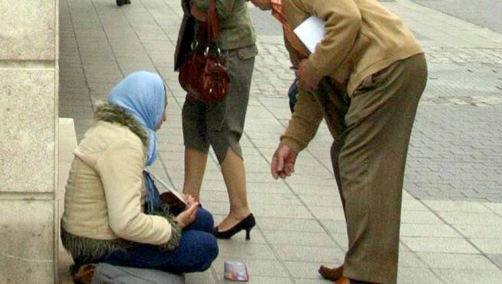 Una mendiga recibe una limosna en la calle Santiago de Valladolid