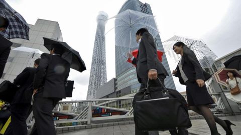 Japoneses que van a su trabajo con la torre de fondo