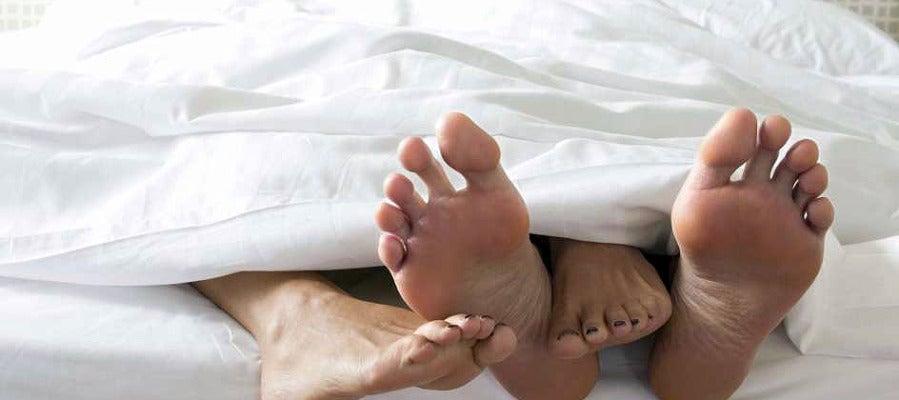 Pies de una pareja en una cama Pies de una pareja en una cama