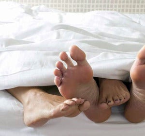 Pies de una pareja en una cama Pies de una pareja en una cama