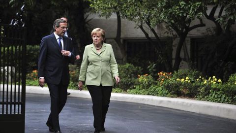 El primer ministro Griego, Andonis Samar&aacute;s, camina junto a la canciller alemana, Angela Merkel