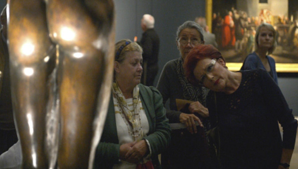 Una visitante observa atentamente una de las esculturas expuestan dentro de la muestra "Hombres desnudos"