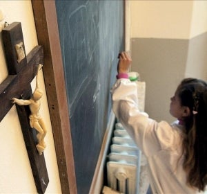 Una alumna escribe en la pizarra de una clase en la que cuelga un crucifijo Una alumna escribe en la pizarra de una clase en la que cuelga un crucifijo