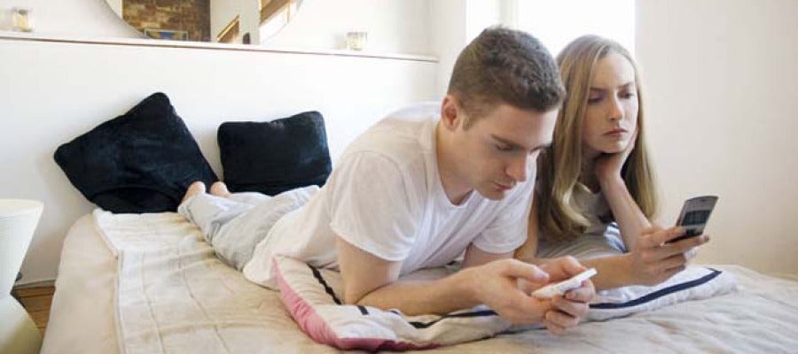 Una pareja utiliza sus móviles en la cama Una pareja utiliza sus móviles en la cama