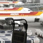 Un carrito de equipajes ante varios aviones de Iberia