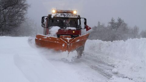 Un cami&oacute;n quitanieves retira la nieve acumulada en una carretera.