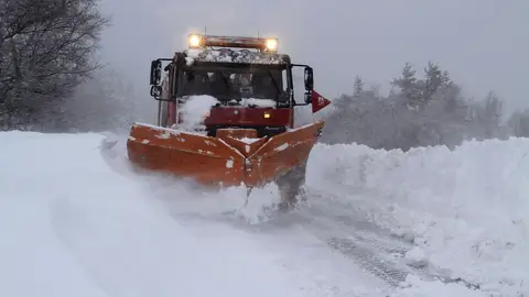 Un camión quitanieves retira la nieve acumulada en una carretera. Un camión quitanieves retira la nieve acumulada en una carretera.