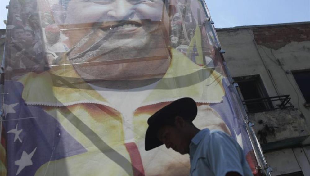 Un hombre pasa frente a una imagen del presidente de Venezuela Hugo Chávez