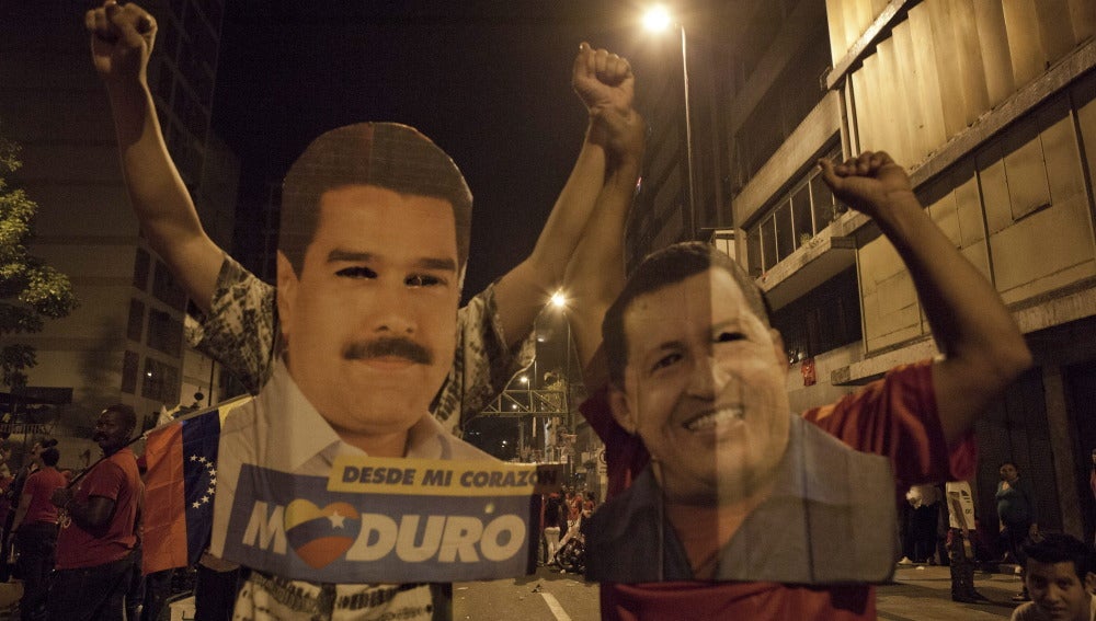 Venezolanos con carteles de Maduro y Chávez