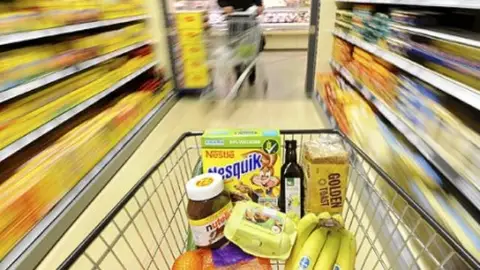 Un carrito de la compra en un pasillo de un supermercado Un carrito de la compra en un pasillo de un supermercado