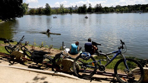 Varias personas descansan junto al lago de la Casa de Campo