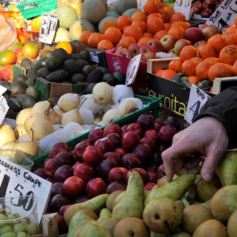 Un vendedor coloca la fruta y verdura en un mercado.