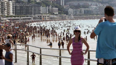 Dos turistas se fotografían junto a la playa de La Concha de San Sebastián.