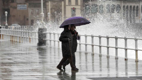 Dos personas pasean por Gij&oacute;n bajo la lluvia