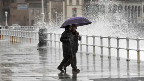 Dos personas pasean por Gijón bajo la lluvia Dos personas pasean por Gijón bajo la lluvia