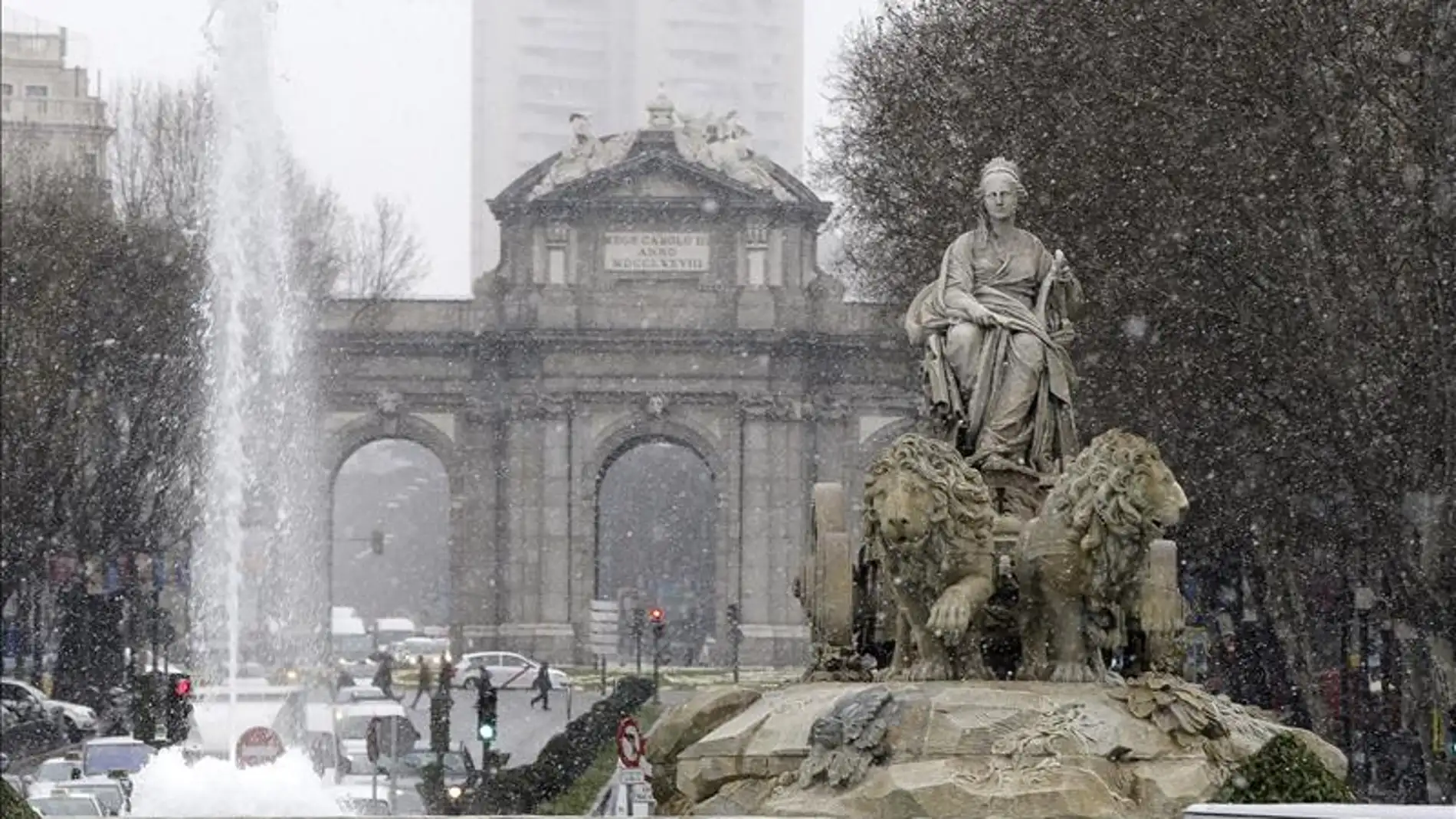 Vista de la Cibeles con la Puerta de Alcalá al fondo, bajo la nieve que cae en Madrid