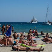 Playa de Ibiza llena de personas tomando el sol