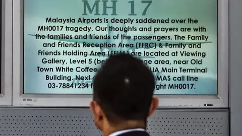 Un pasajero observa una pantalla en la que se lee "Rezo por MH17" Un pasajero observa una pantalla en la que se lee "Rezo por MH17"
