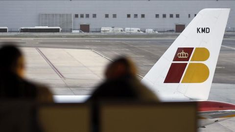 Dos pasajeros contemplan un avi&oacute;n de Iberia
