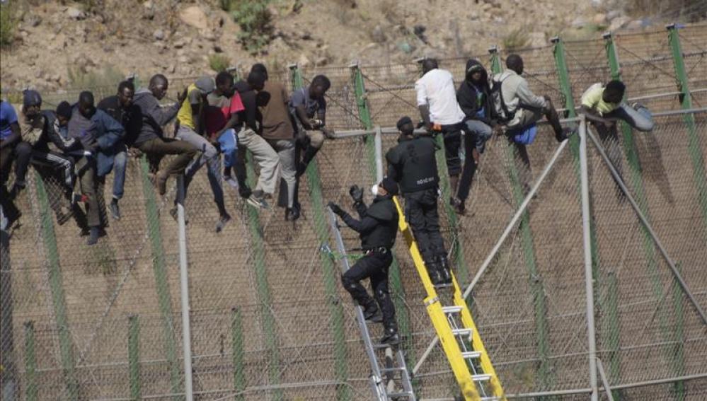 Inmigrantes sobre la valla de Melilla