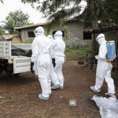 Varios enfermeros liberianos mientras rocían con desinfectante una casa
