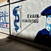 Un niño pasa junto a un mural que representa a un encapuchado junto al anagrama de ETA 