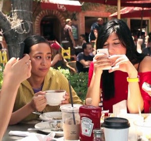Tres personas consultan su teléfono móvil durante una comida Tres personas consultan su teléfono móvil durante una comida