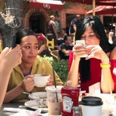 Tres personas consultan su teléfono móvil durante una comida