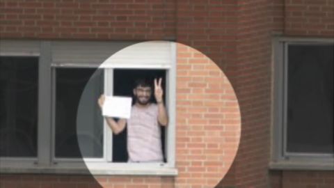 Un joven muestra en un cartel que no tiene fiebre