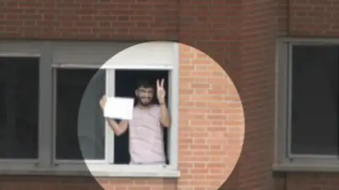 Un joven muestra en un cartel que no tiene fiebre Un joven muestra en un cartel que no tiene fiebre