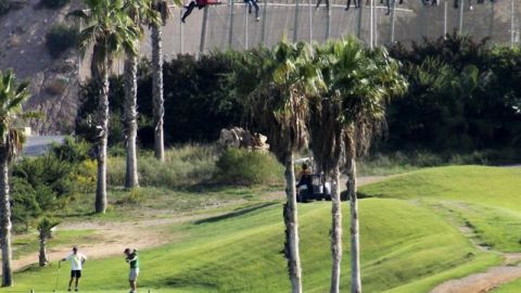 Inmigrantes encaramados a la valla a la altura del campo de golf de Melilla
