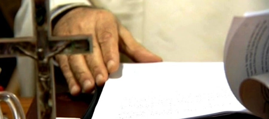 Un religioso con documentos y un crucifijo Un religioso con documentos y un crucifijo
