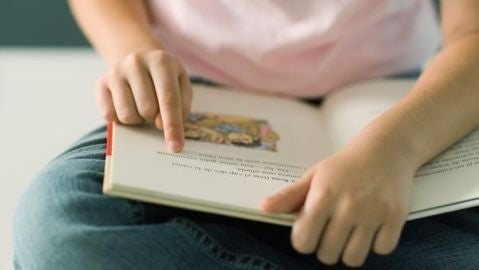 Una ni&ntilde;a lee un libro de texto.