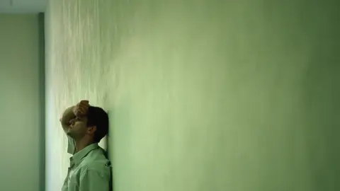 Un joven reposa la cabeza sobre ya pared. Un joven reposa la cabeza sobre ya pared.