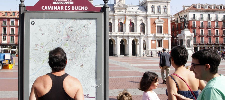 Una familia de turistas observa el panel informativo de las rutas 'Caminar es bueno' en la Plaza Mayor de Valladolid Una familia de turistas observa el panel informativo de las rutas 'Caminar es bueno' en la Plaza Mayor de Valladolid