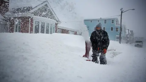 Un hombre retirando nieve frente a su casa Un hombre retirando nieve frente a su casa