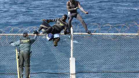 Imagen de archivo en la que dos inmigrantes intentan saltar la valla en Ceuta Imagen de archivo en la que dos inmigrantes intentan saltar la valla en Ceuta