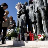 Varias personas depositan flores y velas junto al monumento en memoria de los fallecidos del 11M
