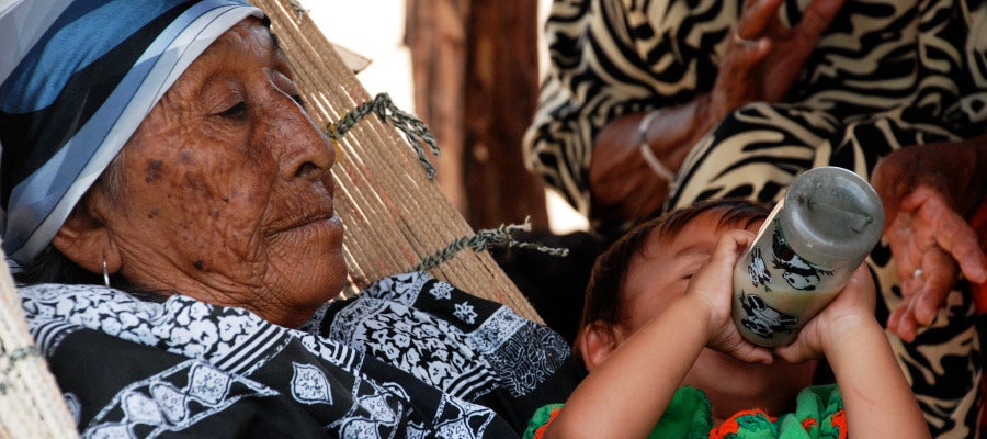 Una abuela de Colombia cuida de su nieto mientras toma un biberon Una abuela de Colombia cuida de su nieto mientras toma un biberon