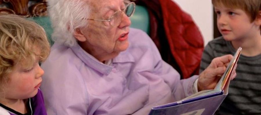 Una anciana leyéndole un cuento a dos niños Una anciana leyéndole un cuento a dos niños